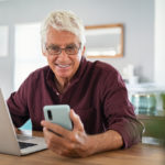 Senior man working on laptop and using smartphone